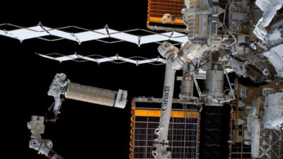 Josh Cassada holding a roll-out solar array via the Canadarm2 robotic arm