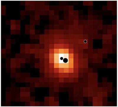 Map of the distant galaxy J0148-4214 in ionised hydrogen (Hα). The locations of the three massive black holes are indicated by black circles (not to scale). The most massive and least massive black holes are located in the galaxy centre; a third black hole is located in the galaxy outskirts. Credit: Hannah Übler